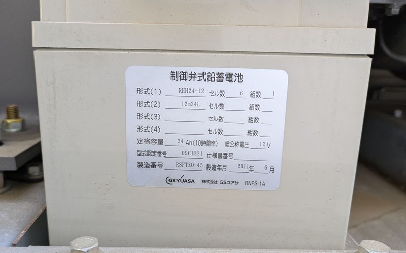 据置蓄電池の銘板（形式REH24-12・セル数6・組数1・定格容量24Ah・総公称電圧12V）